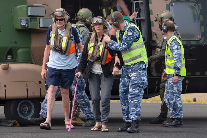 people stand next to and site inside a helicopter labelled 'hat-trick'