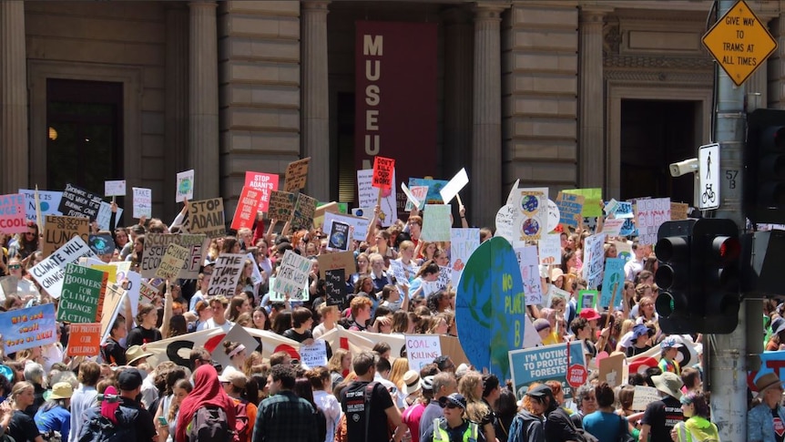 A large group of students holds up colourful signs.
