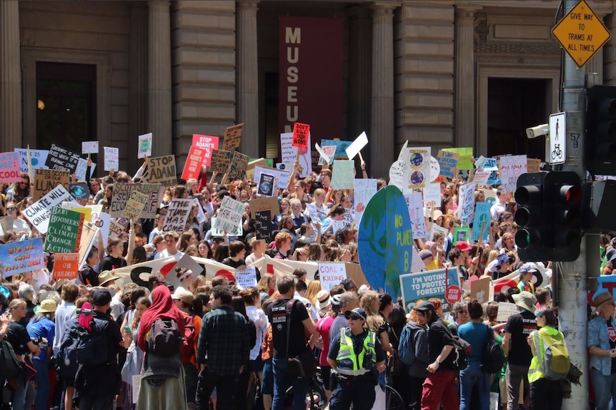 A large group of students holds up colourful signs.