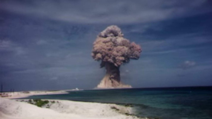 A plume of smoke rises over the seashore