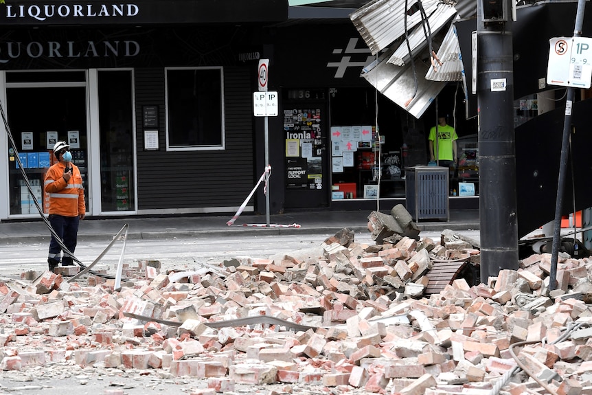 A person in high vis looks at building with bricks scattered on the ground. Ausnew Home Care, NDIS registered provider, My Aged Care