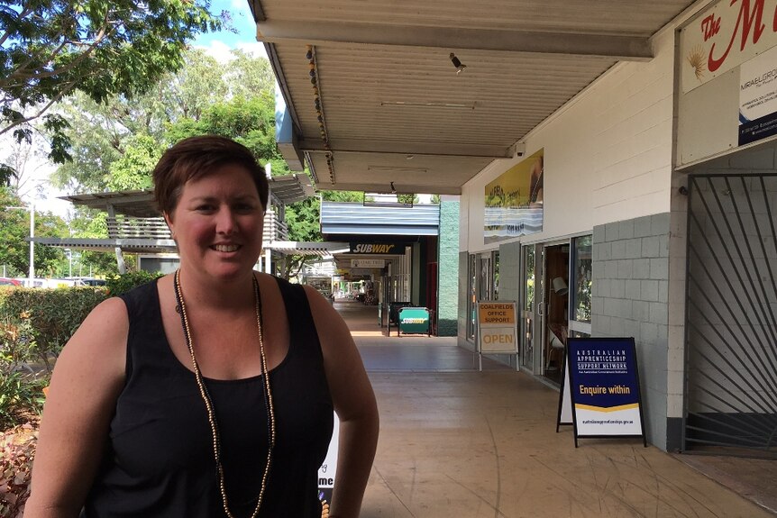 A business owner stands in front of shops in the business centre of Moranbah