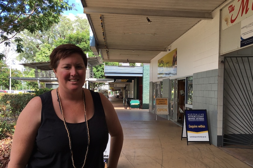 A business owner stands in front of shops in the business centre of Moranbah