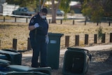 A police officer takes photographs in suburban Alice Springs.