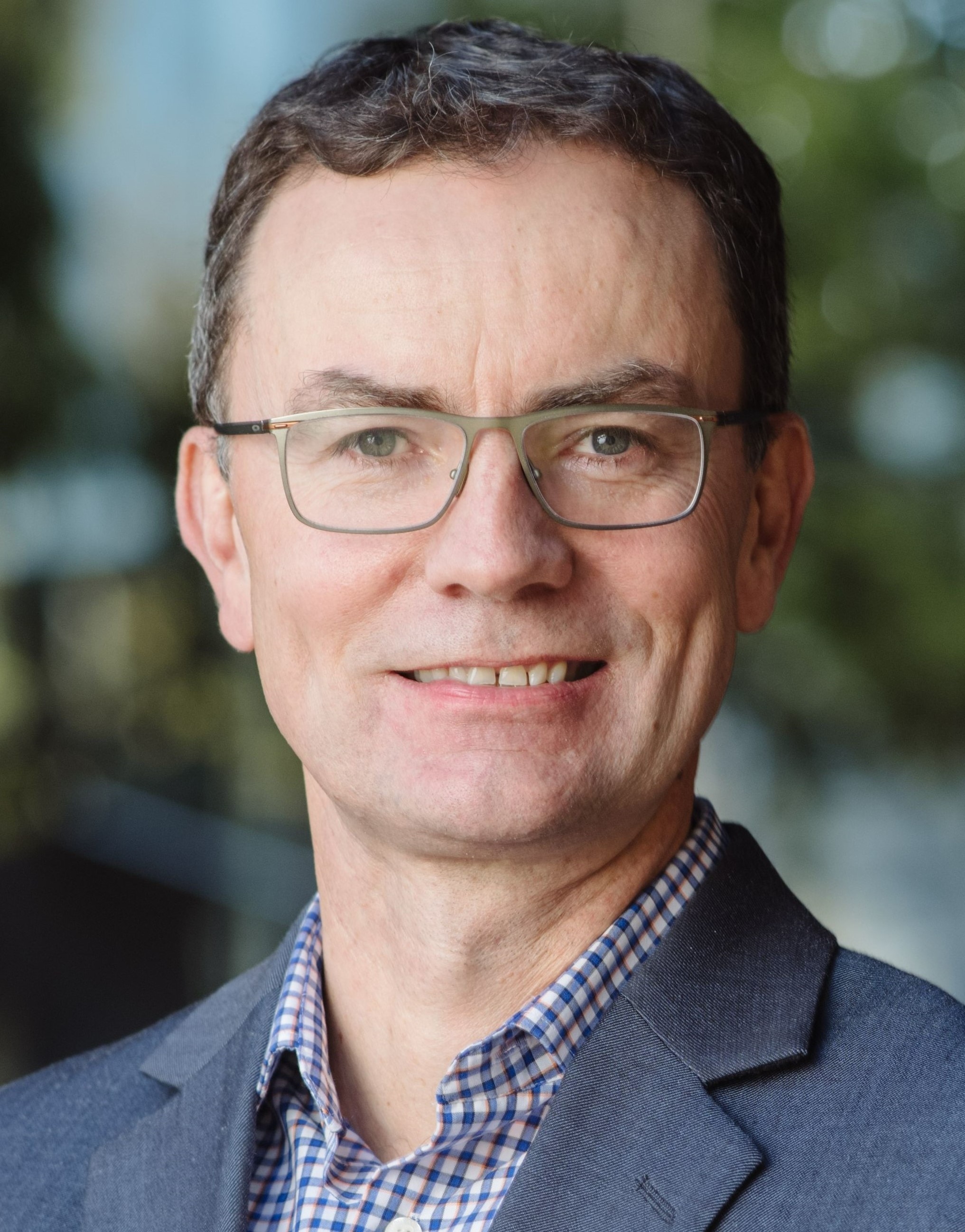 A headshot of a man with glasses and dark hair. 