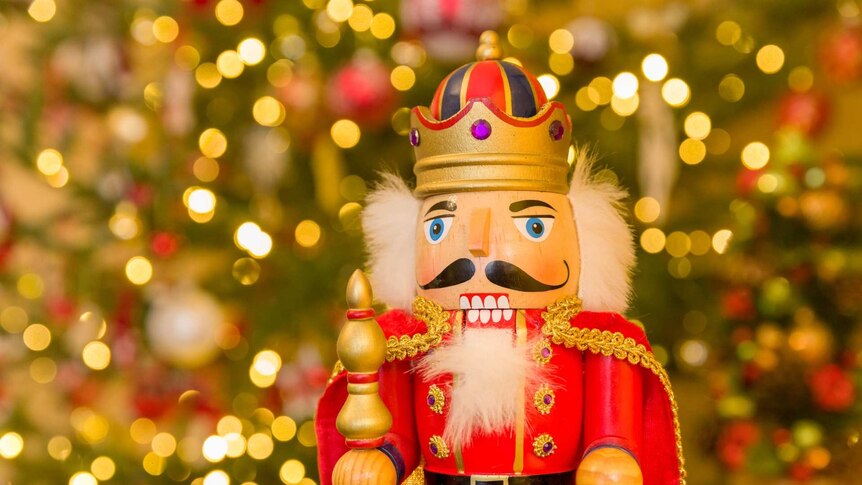 A traditional Christmas nutcracker in front of a Christmas Tree