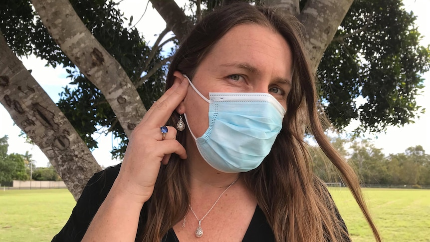 A woman wearing a mask signs in Auslan to say she is deaf.