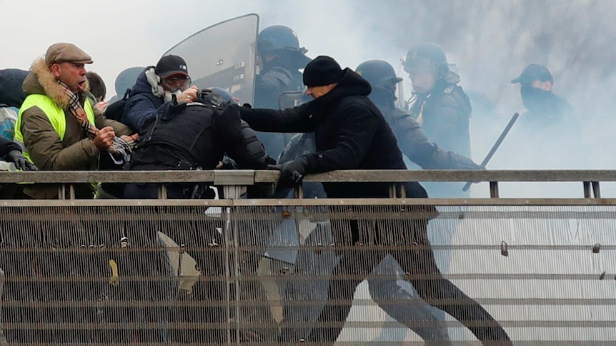 Former French boxing champion, Christophe Dettinger reaches out his arm in front of a line of police.
