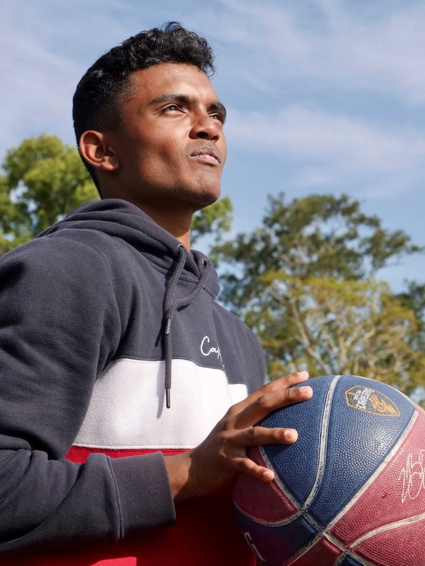 A young man holds a basketball.