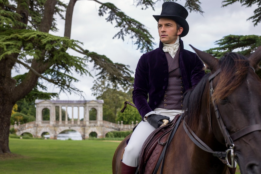 A man on a horse dressed in period attire and top hat