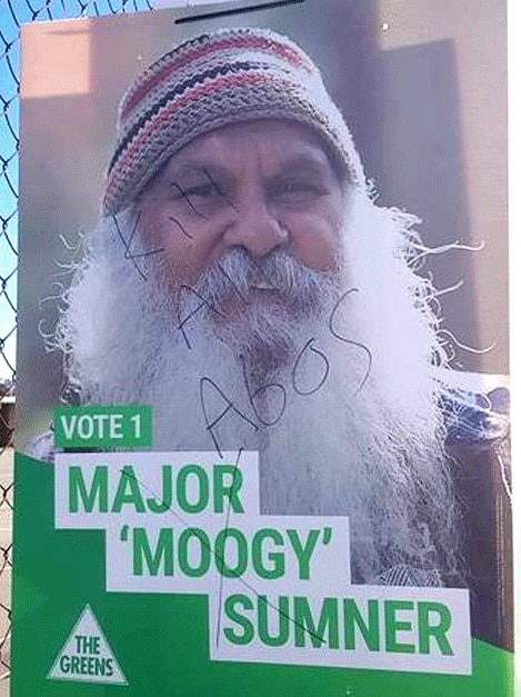 A campaign poster with the face of an Aboriginal man with a beard that has a racist slogan written on the front