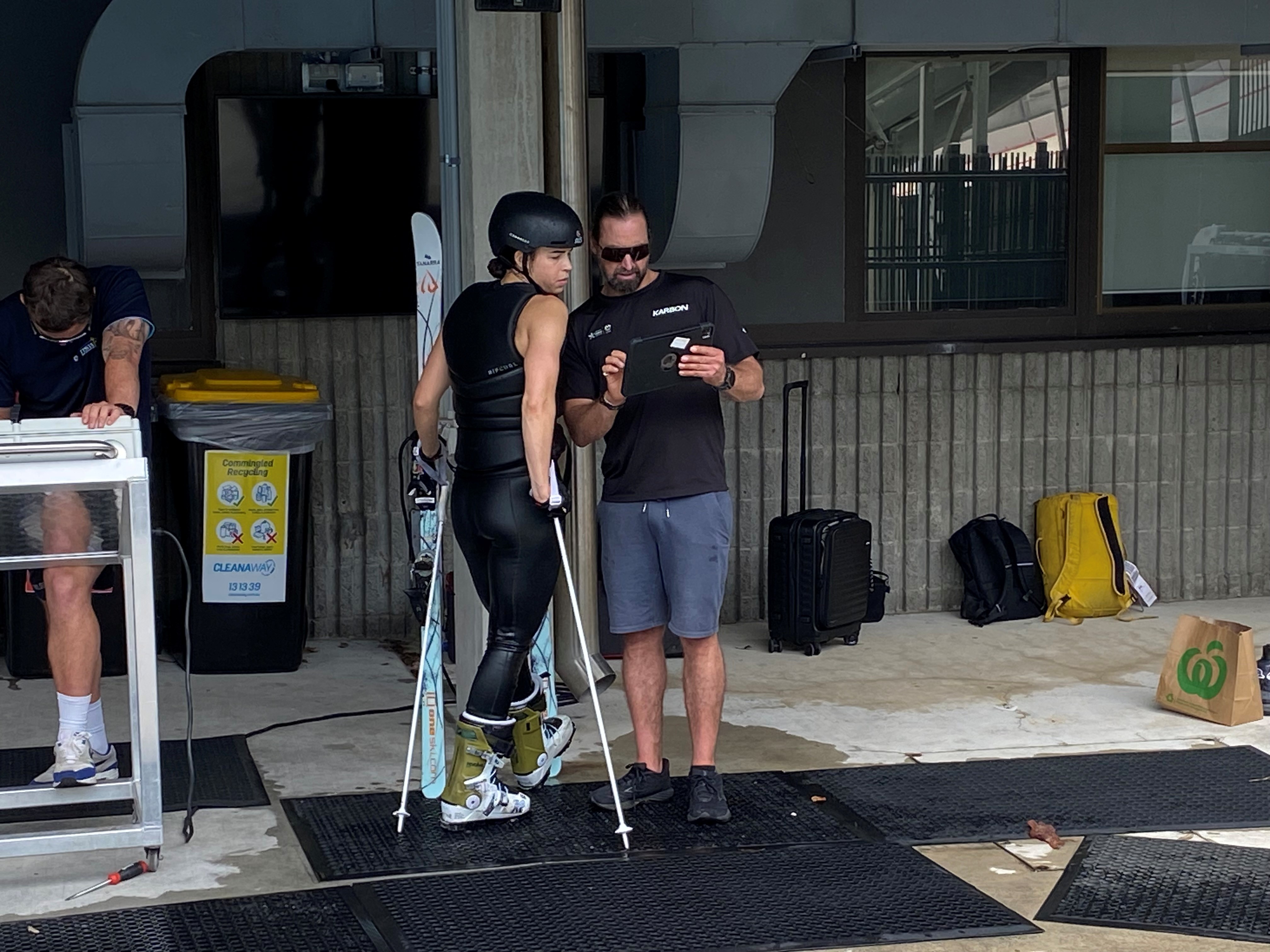 A woman in a helmet looks at an iPad held by a dark-haired man.