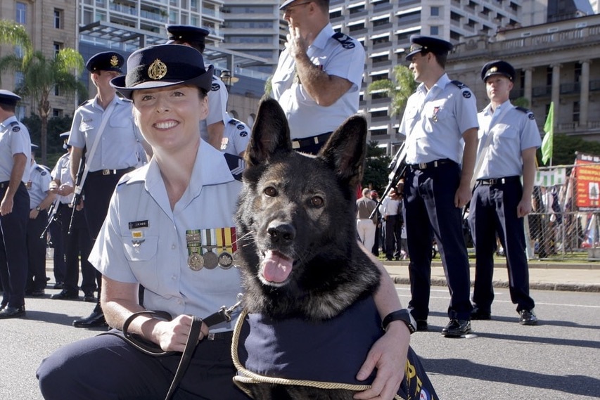 Autumn Bell in uniform, crouching and patting a dog. She is outside.