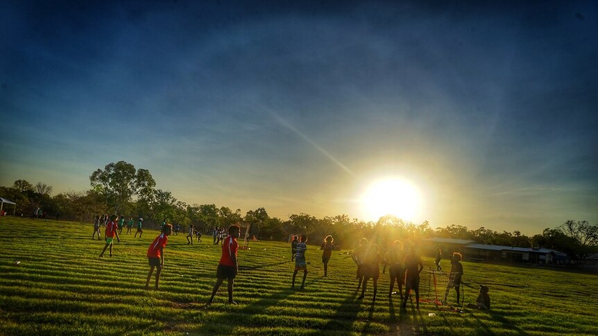 Children play soccer as the sun sets