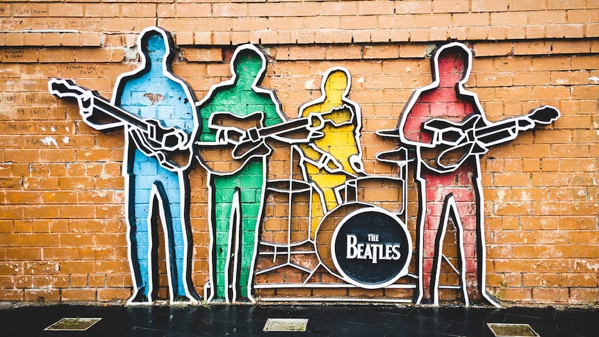 An artwork depicting silhouettes of the four members of the Beatles, rendered in primary colours on an outdoor brick wall