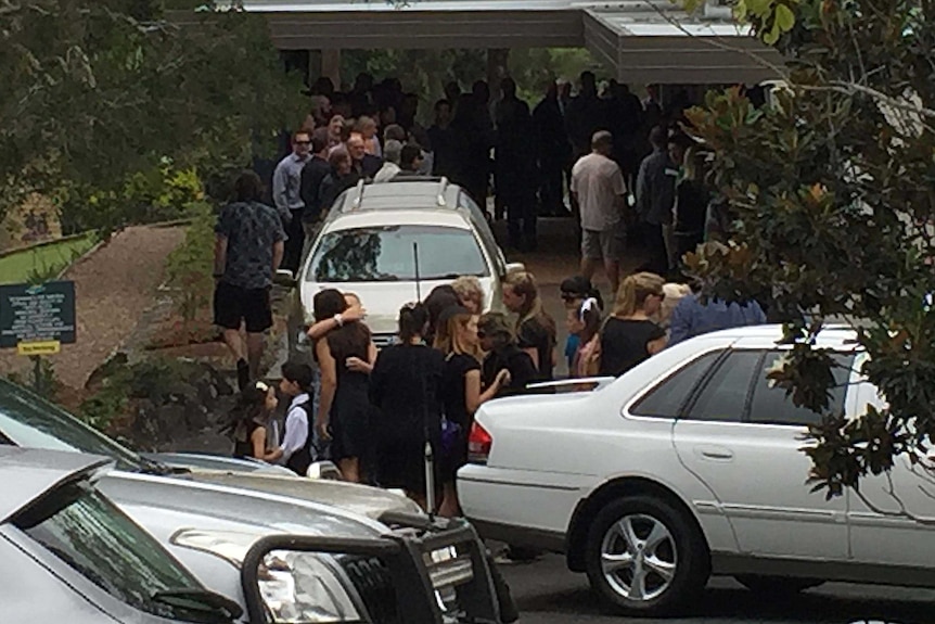 People hug outside the funeral of Peter Fanning, the brother of surfer Mick Fanning.