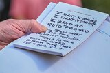 The hand of Donald Trump holds a notepad with notes written in thick black texta, which reads 'I want nothing' twice.
