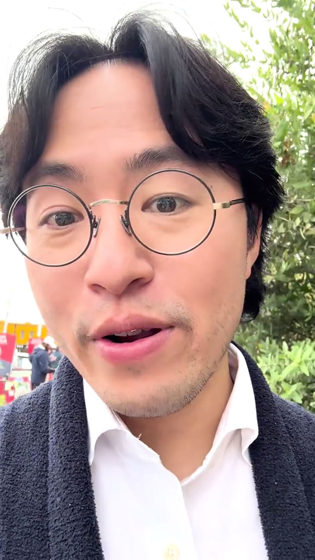 A young man with black hair and glasses looks into the lens