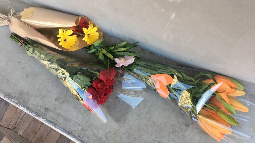 Three bunches of flowers on concrete seat at Oatley train station in Sydney.