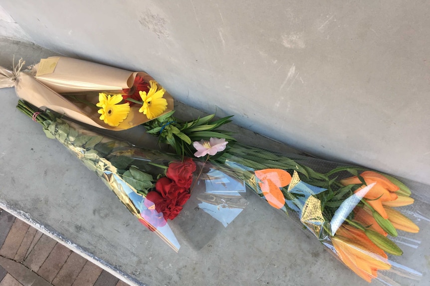 Three bunches of flowers on concrete seat at Oatley train station in Sydney.