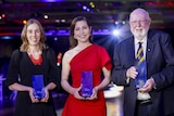 Three people pose with awards.