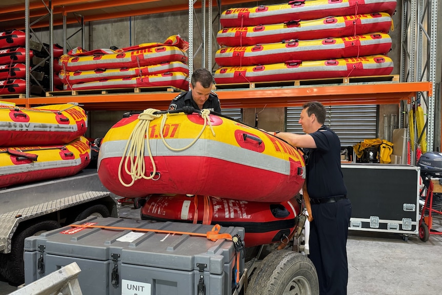 Firefighters in uniform loading an inflatable boat.
