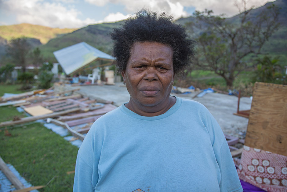 Woman looks concerned standing out front of cyclone-damaged buildings