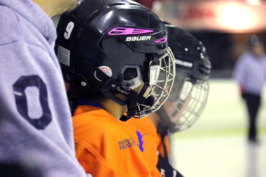 New South Wales bench and coach watch on as the team plays ACT in broomball in an ice rink.