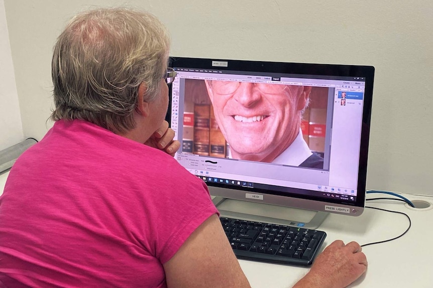 A woman whitens a man's teeth in a photo editing application on a computer.