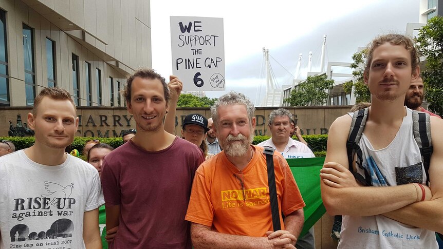 Four men and other protestors standing outside court in Brisbane