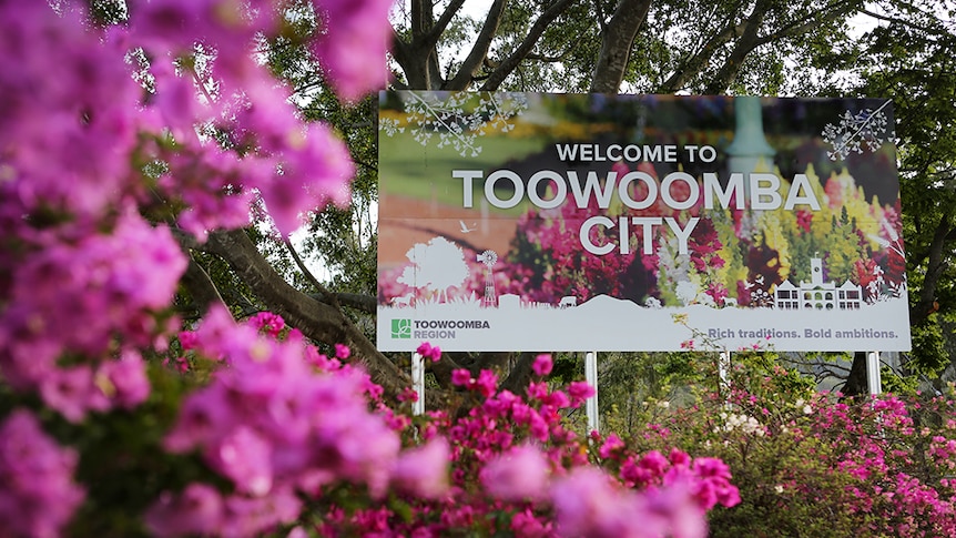 The Toowoomba welcome sign surrounded by pink flowers.