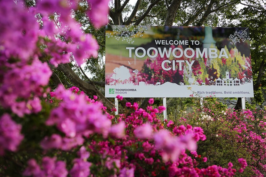 The Toowoomba welcome sign surrounded by pink flowers.