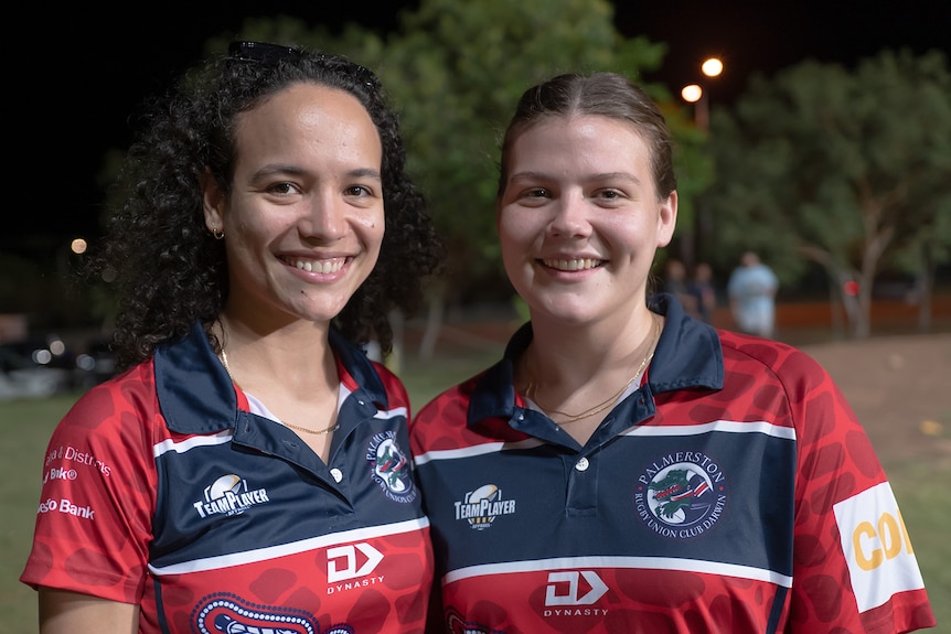 Two women in red and blue polos smile at the camera.