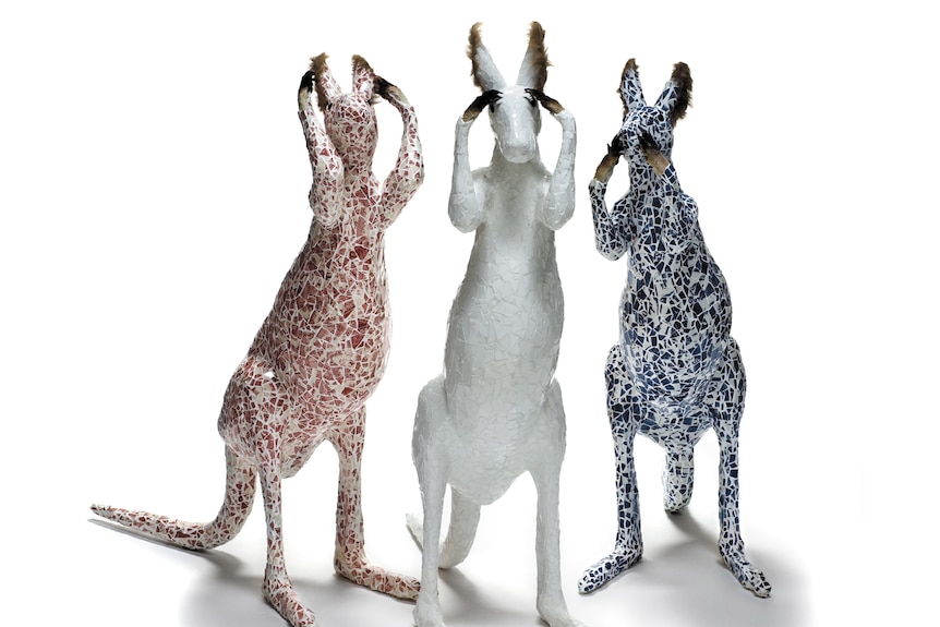 A sculpture of three kangaroos, one red, one white and one blue.