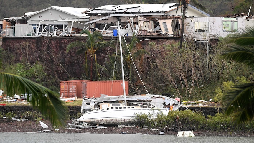 A boat is seen smashed against a bank at Shute Harbour