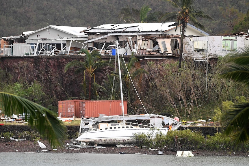 A boat is seen smashed against a bank at Shute Harbour
