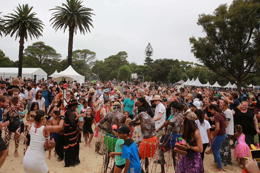 A crowd joins Aboriginal dancers performing outside at the festival.
