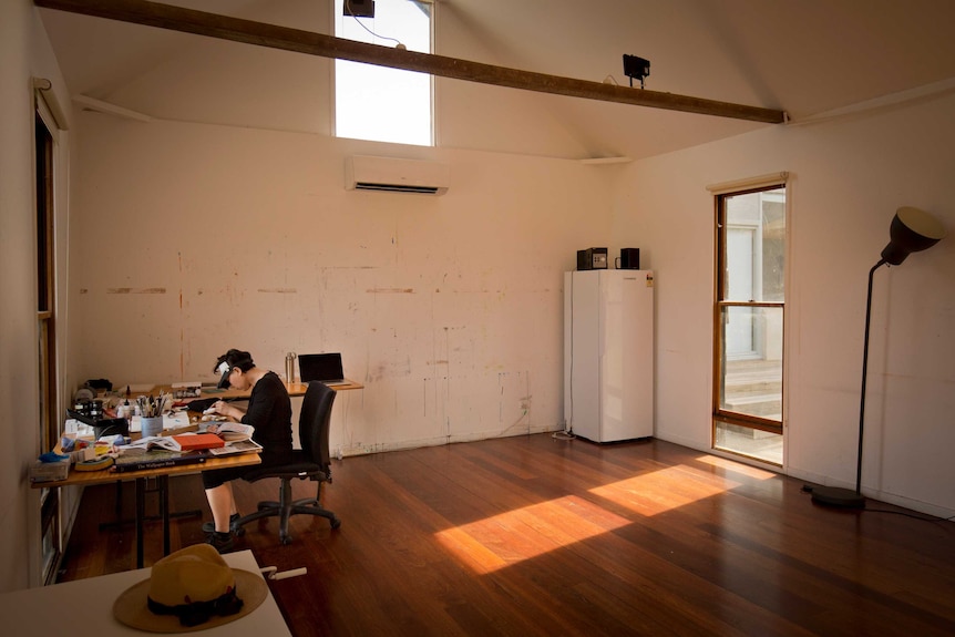 A woman alone working on art in a room.