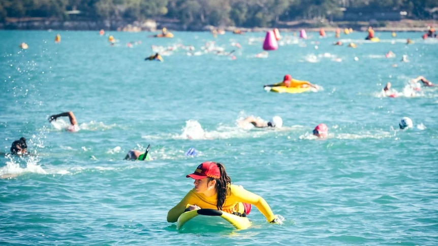 Lifeguard in front of many swimmers in open water Darwin Harbour.