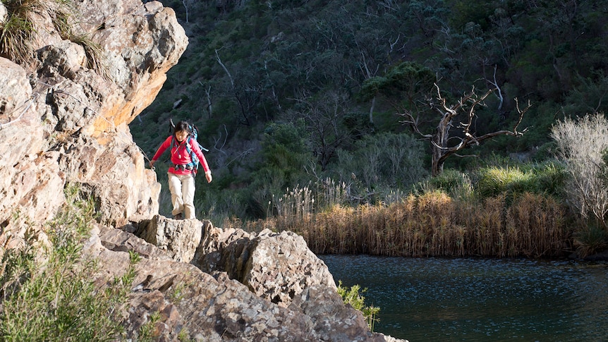 A woman walks around a large rock face in Werribee Gorge.