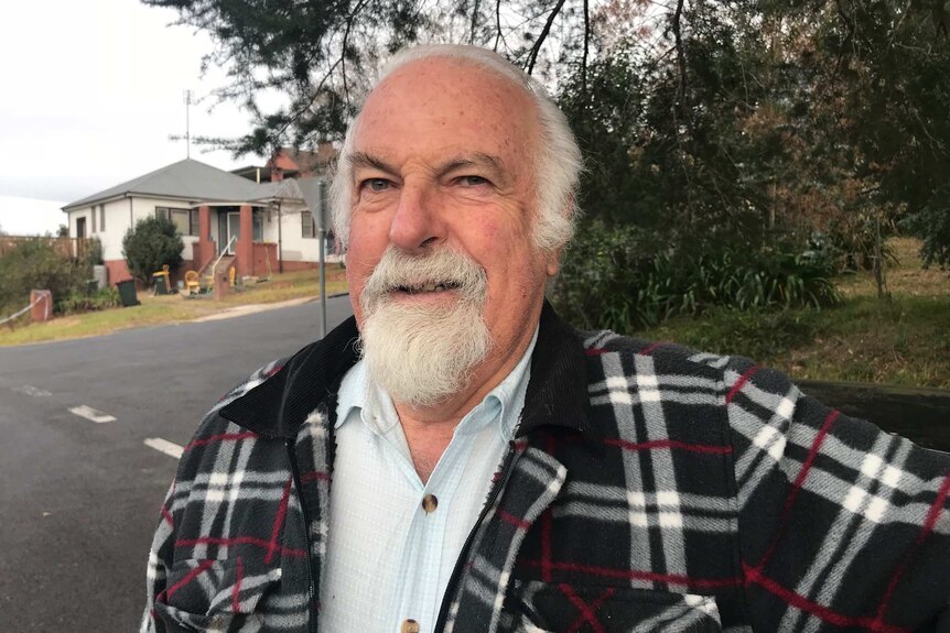 Bob Russell smile while standing on a suburban street.