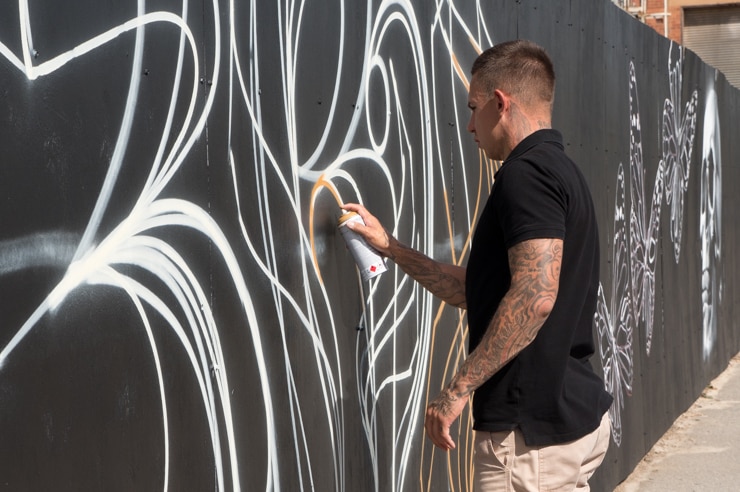 Local artist Shane Cook spray paints a line on his piece.