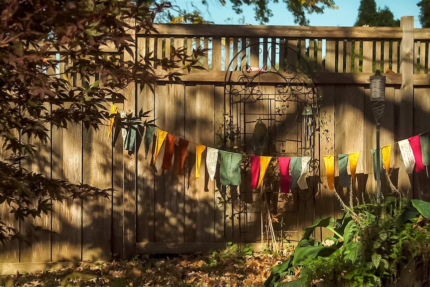 Colourful pray flags strewn on a fence in a backyard