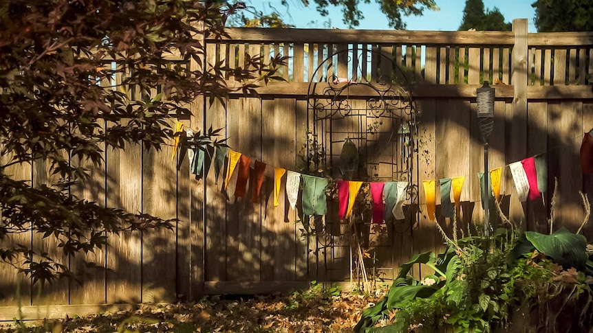 Colourful pray flags strewn on a fence in a backyard