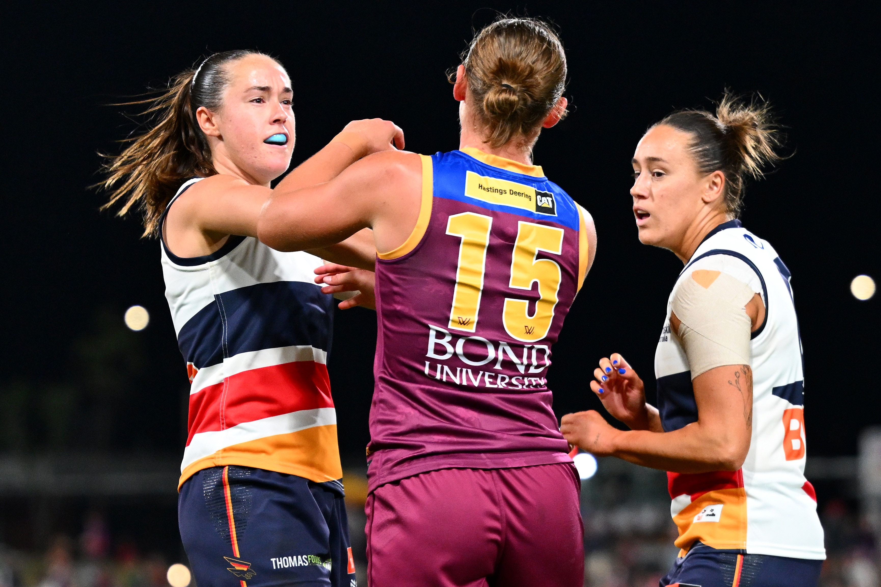 Two AFLW players, one in red and blue and one in white, tussle.
