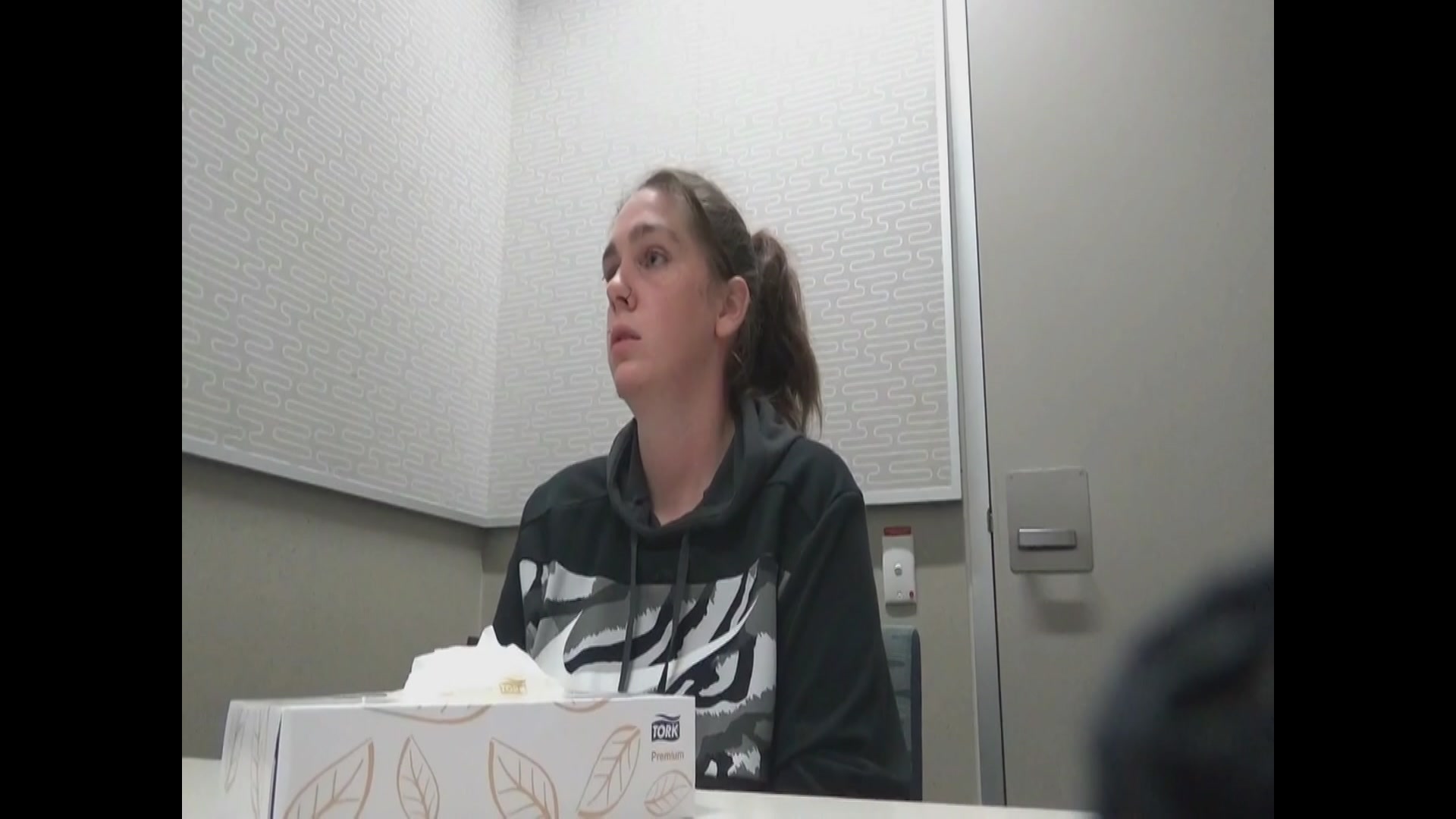 Una mujer sentada en una silla y mira hacia la derecha.