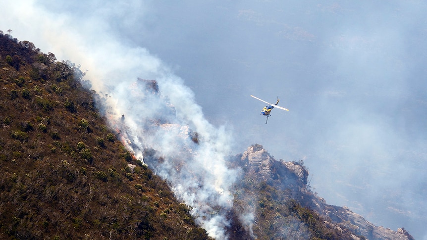 A helicopter flies near smoke from a Tasmanian bushfire