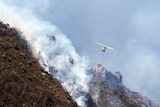 A helicopter flies near smoke from a Tasmanian bushfire