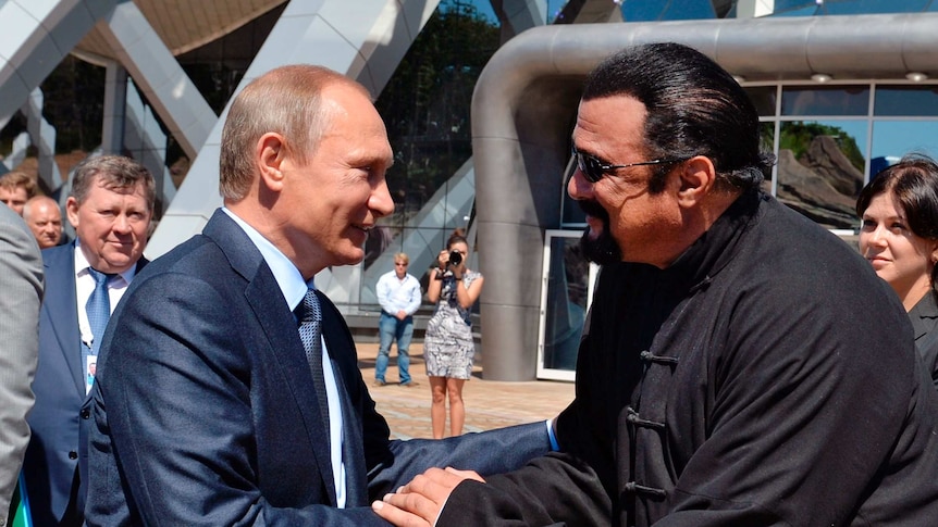 Vladimir Putin (L) and Steven Seagal (R) shake hands