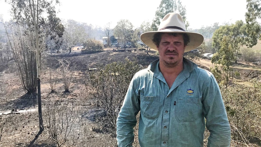 Nathan Corbett stands in front of scorched and his uncle's house, which he fought to save from the bushfire